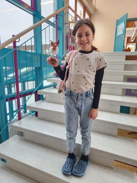 Kind steht auf einer Treppe und zeigt einen gebastelten Weihnachtselch