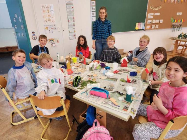 Gruppe von Kindern sitzt um einen Tisch mit Bastelmaterialien