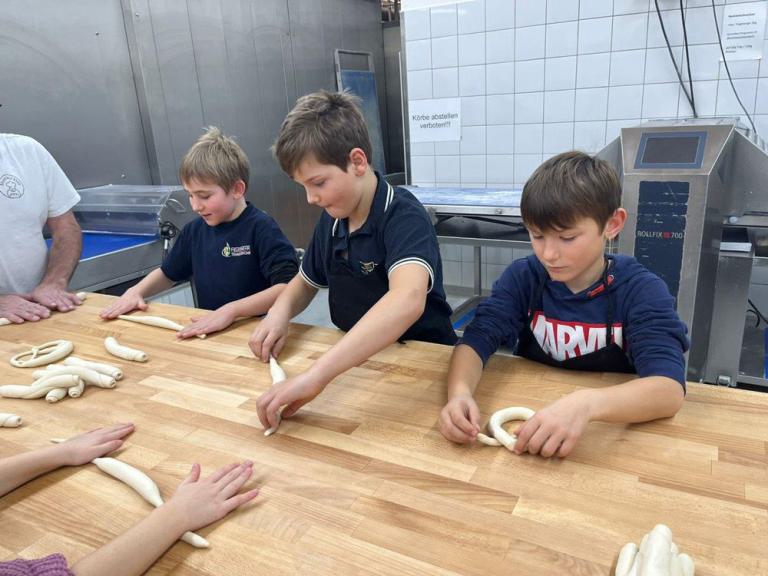 Drei Jungen formen Brezeln aus Teig