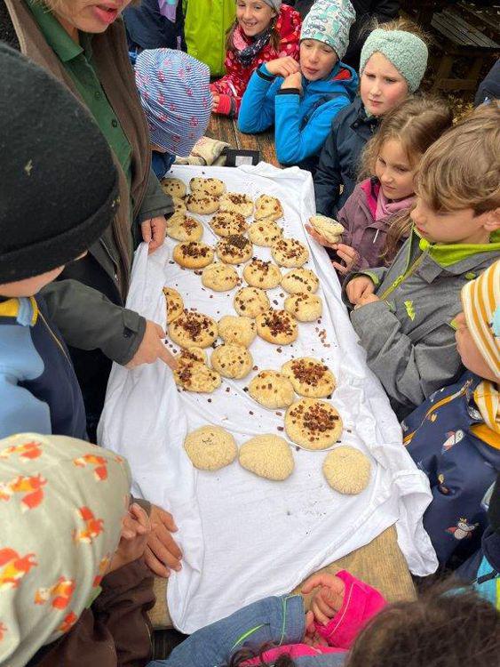 Mehrere Kinder stehen um einen Tisch mit Dinnede auf weißer Tischdecke