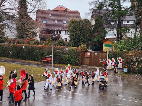 Narren mit Katzenmasken laufen über den nassen Schulhof
