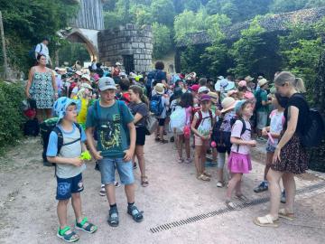 Viele Schüler vor imposanten Steinruinen in einem bewaldeten Außenbereich.